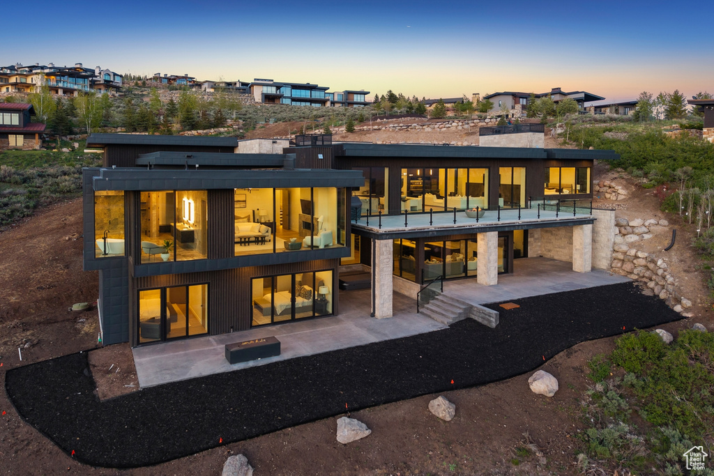 Back of property at dusk featuring a patio area and a balcony