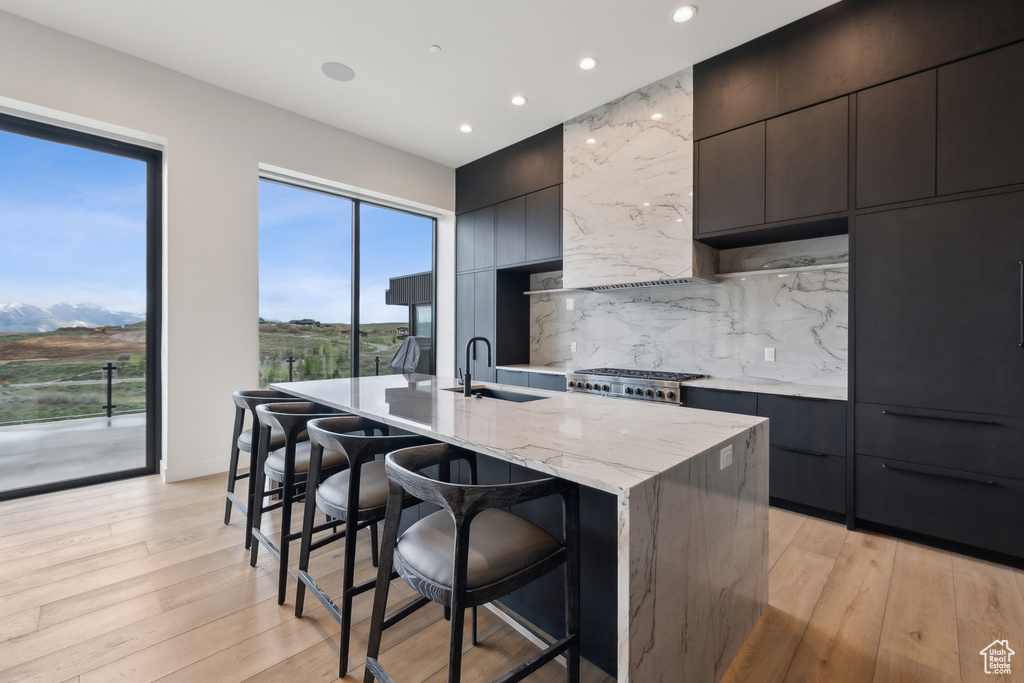 Kitchen featuring a sink, modern cabinets, a kitchen bar, a kitchen island with sink, and recessed lighting