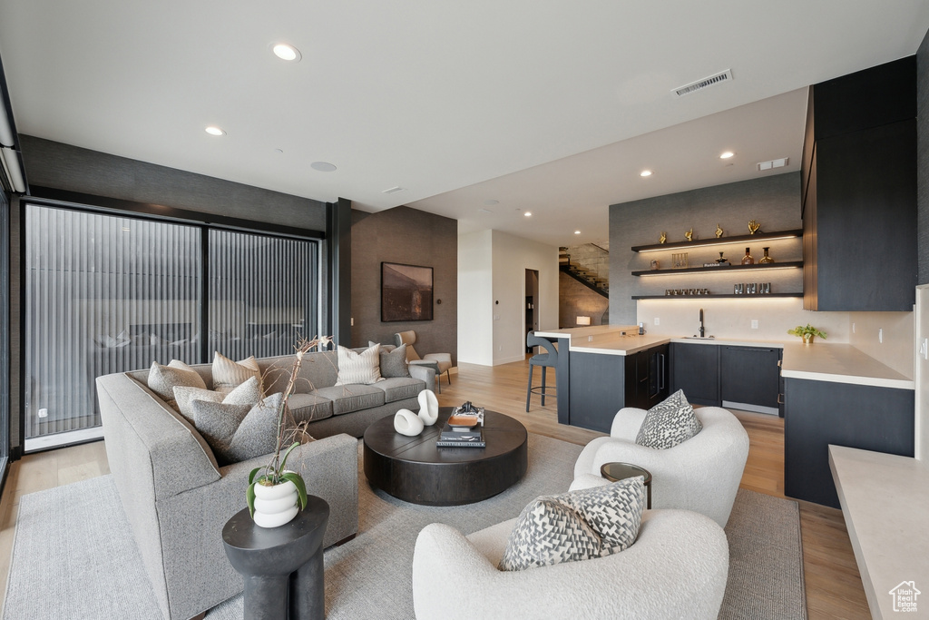 Living area featuring light wood finished floors, wet bar, and recessed lighting