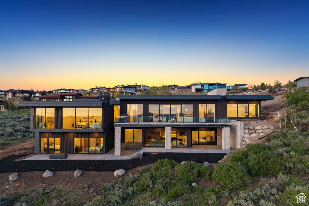Back of property at dusk with a patio area and a balcony