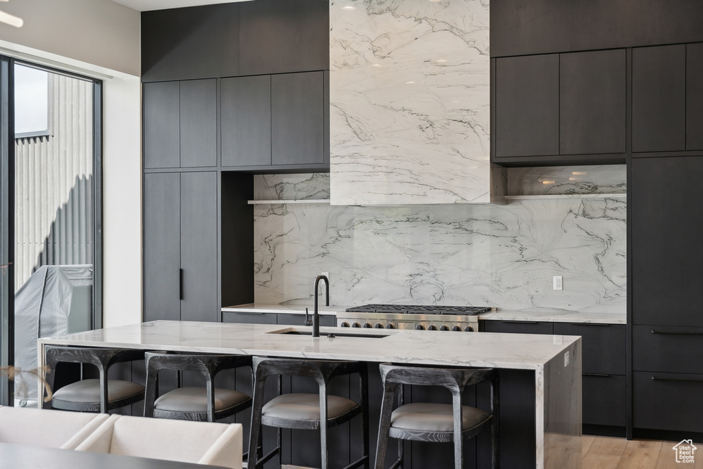 Kitchen featuring modern cabinets, a kitchen breakfast bar, a sink, light stone countertops, and decorative backsplash