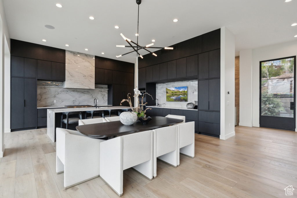 Kitchen with modern cabinets, recessed lighting, a chandelier, a center island with sink, and decorative backsplash