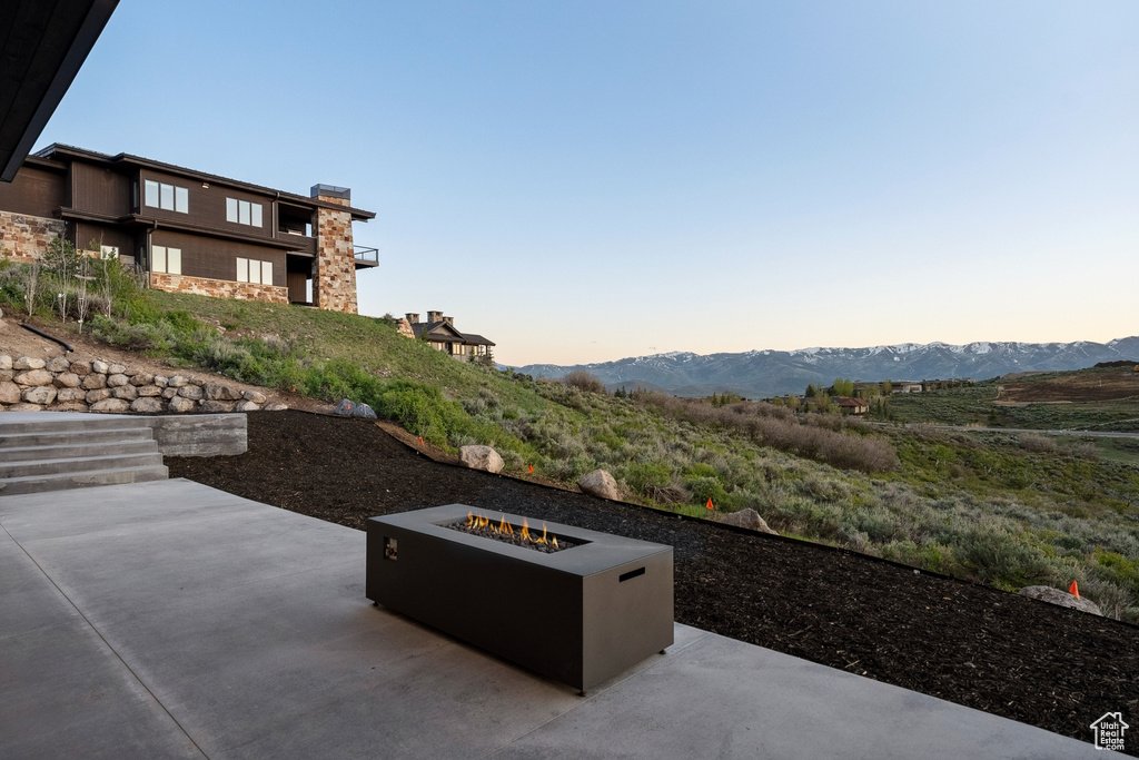 Patio terrace at dusk featuring an outdoor fire pit, a patio, and a mountain view
