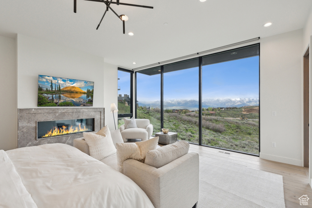 Bedroom featuring floor to ceiling windows, a premium fireplace, light wood-style flooring, access to exterior, and recessed lighting