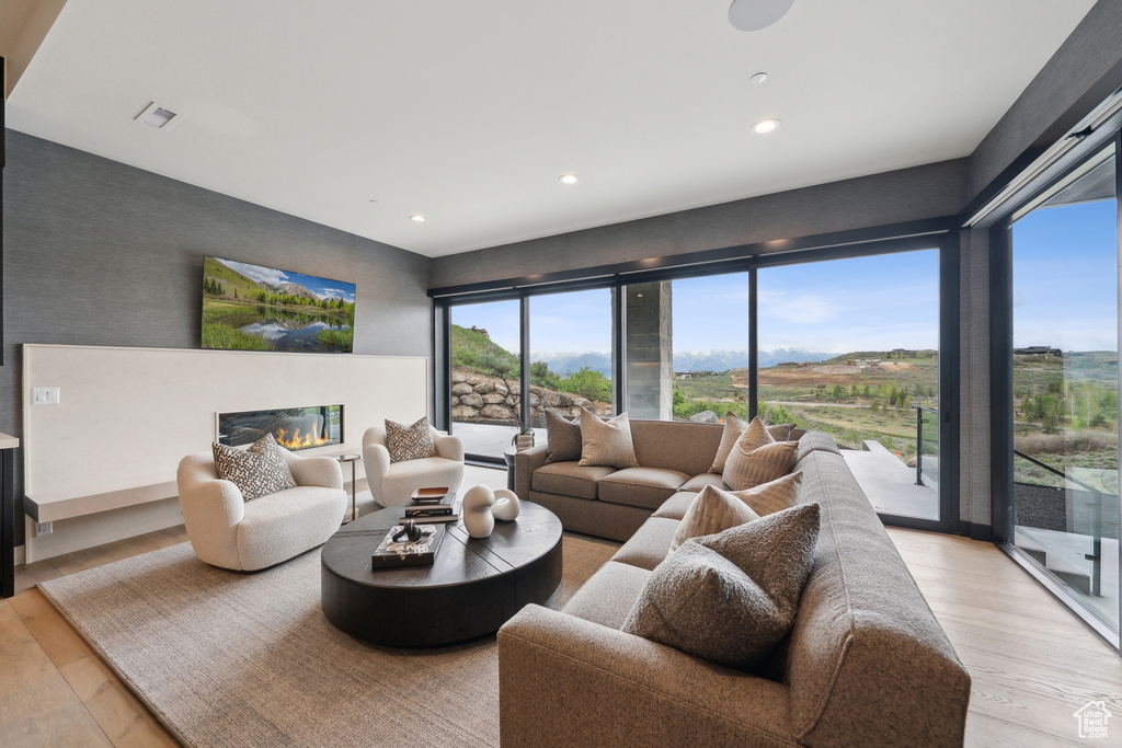 Living area featuring light wood-type flooring, recessed lighting, and a glass covered fireplace