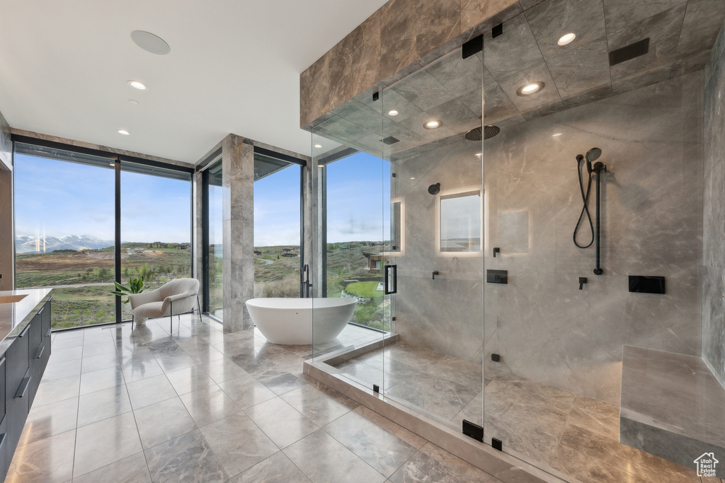 Bathroom featuring a soaking tub, a stall shower, vanity, and floor to ceiling windows