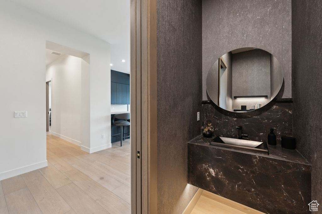 Bathroom featuring decorative backsplash, wood finished floors, vanity, and baseboards