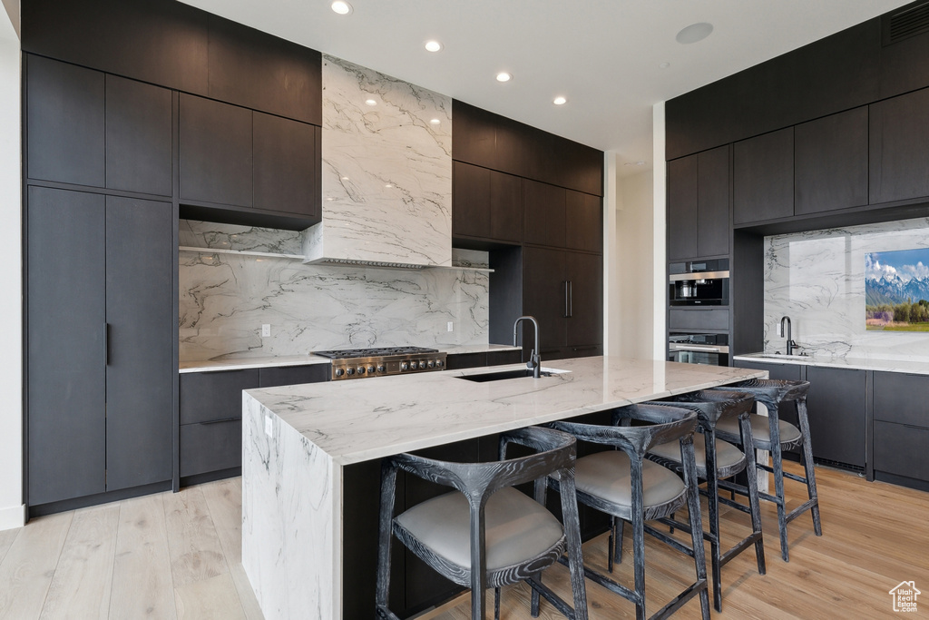Kitchen with a sink, stainless steel oven, modern cabinets, a breakfast bar, and tasteful backsplash