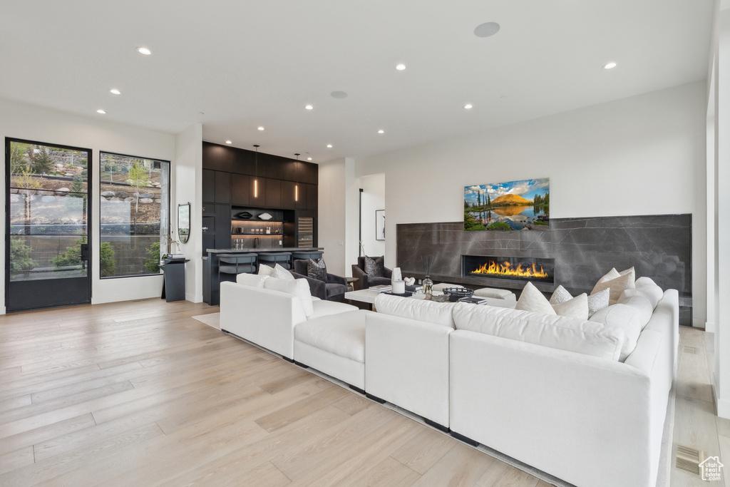 Living area with a glass covered fireplace, recessed lighting, and light wood-style floors