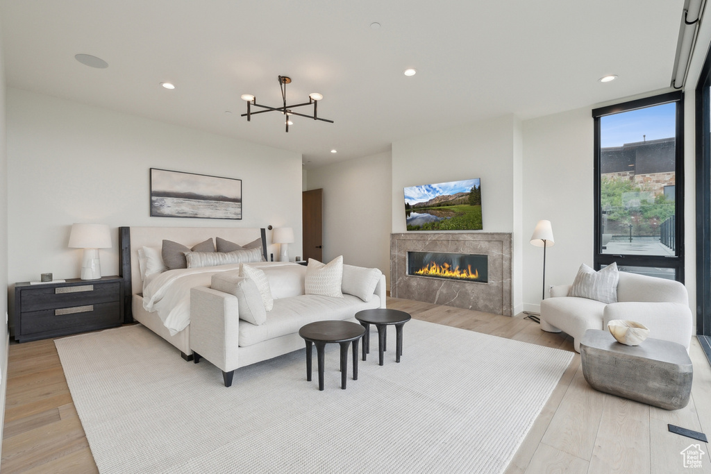 Bedroom featuring light wood finished floors, a chandelier, a tiled fireplace, and recessed lighting