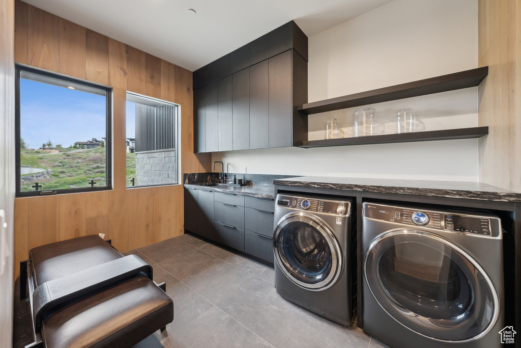 Laundry room with separate washer and dryer, wooden walls, and a sink
