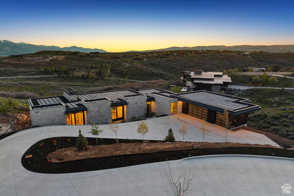 View of front of home featuring a mountain view, concrete driveway, a garage, and stone siding