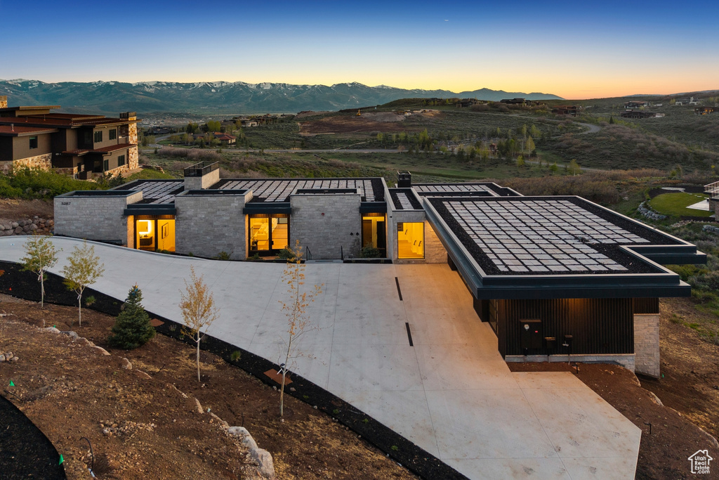 View of front of property featuring a mountain view, a chimney, curved driveway, and a standing seam roof
