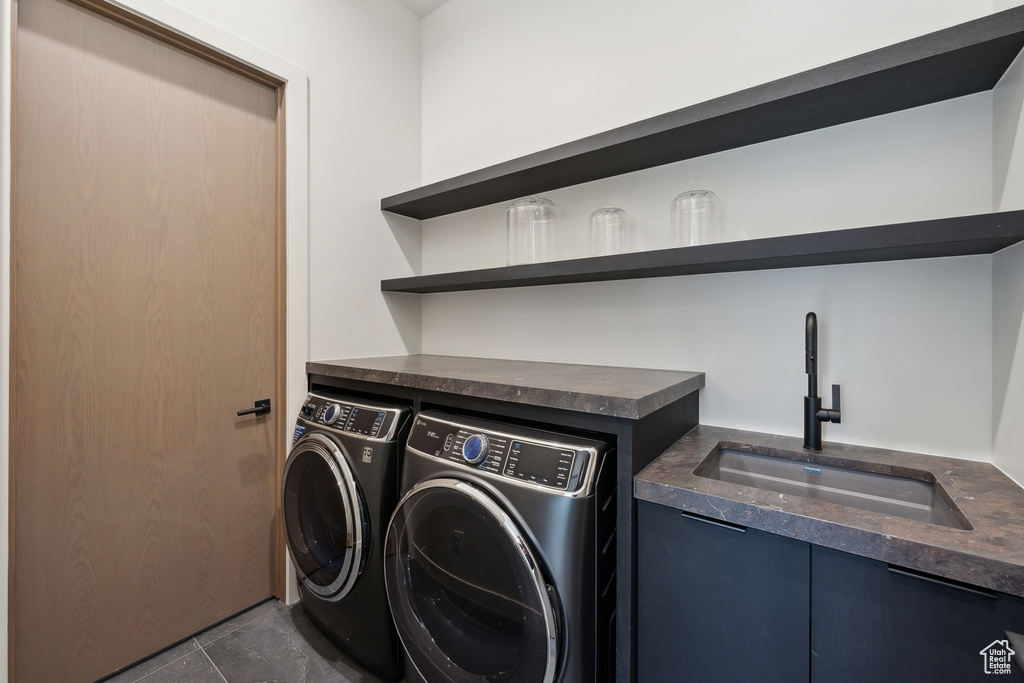 Laundry area featuring independent washer and dryer, dark tile patterned flooring, and bar