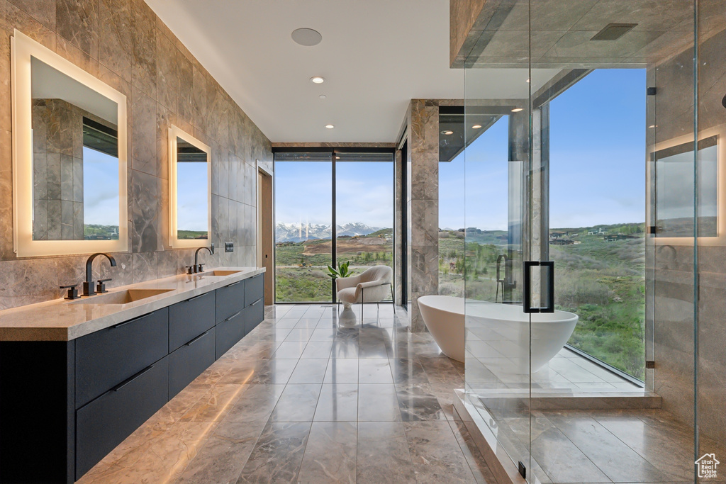 Full bathroom with marble tiled floors, a freestanding tub, double vanity, floor to ceiling windows, and a mountain view