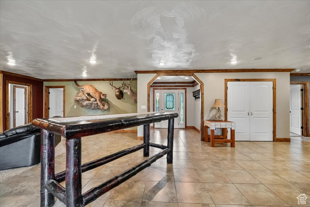 Rec room with light tile patterned floors and ornamental molding