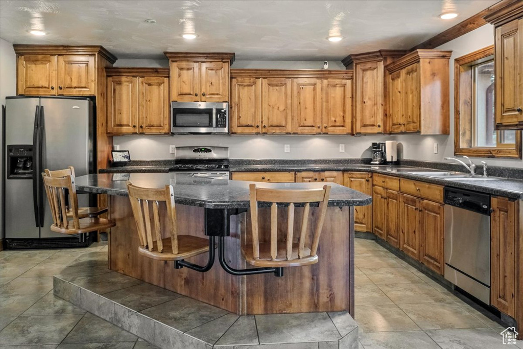 Kitchen with a center island, sink, a breakfast bar area, dark stone countertops, and stainless steel appliances