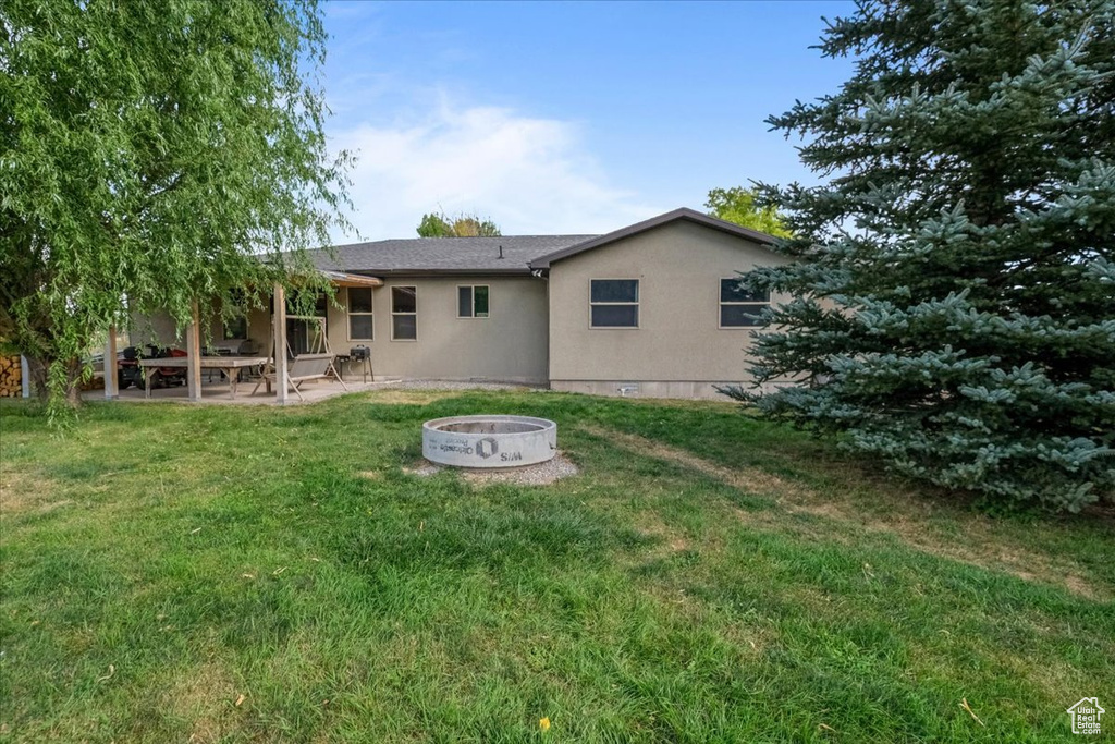 Rear view of house with a yard, a patio, and a fire pit
