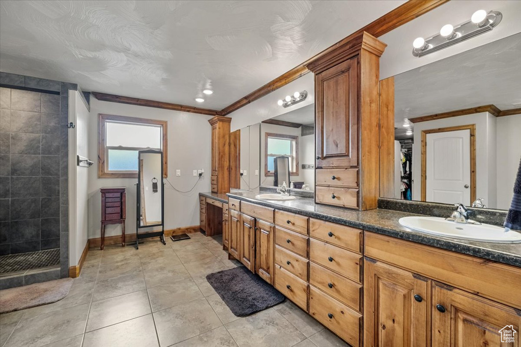 Bathroom featuring tile patterned floors, a shower, vanity, and ornamental molding