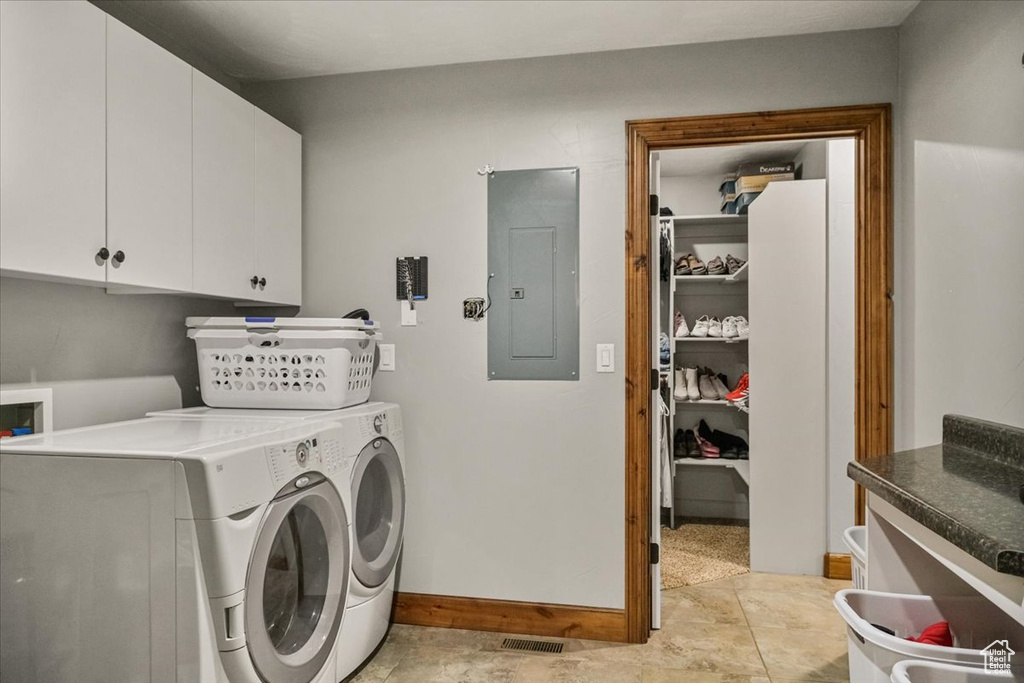 Laundry area with cabinets, washing machine and dryer, and electric panel
