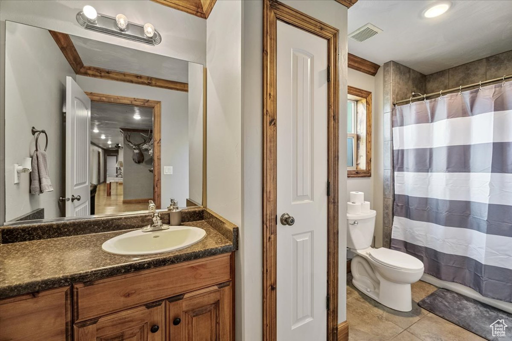 Bathroom featuring ornamental molding, vanity, tile patterned flooring, toilet, and curtained shower