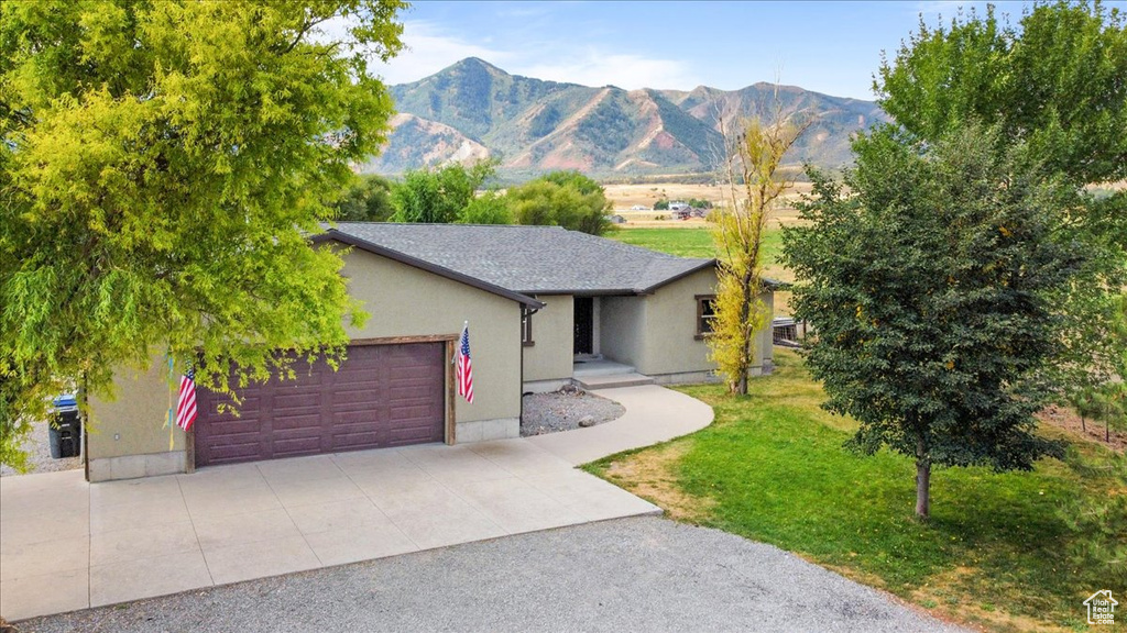 Ranch-style house with a mountain view, a front yard, and a garage