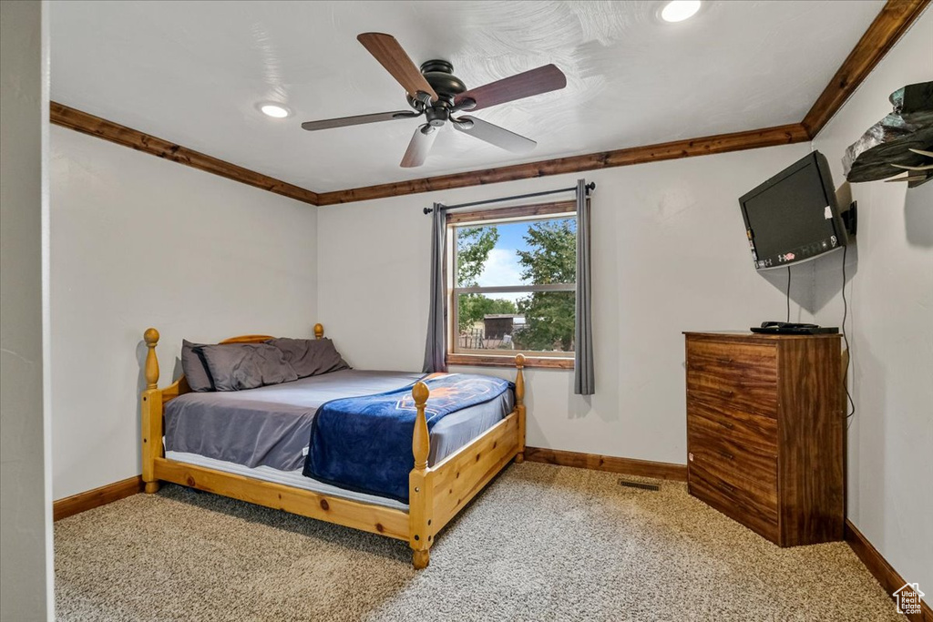 Carpeted bedroom featuring ceiling fan and ornamental molding