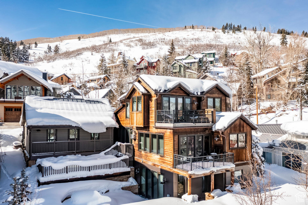 Snow covered back of property featuring a balcony