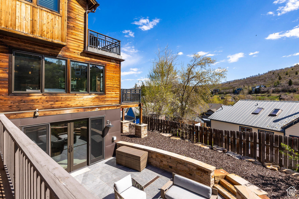 Fenced backyard with a balcony, a patio, and french doors