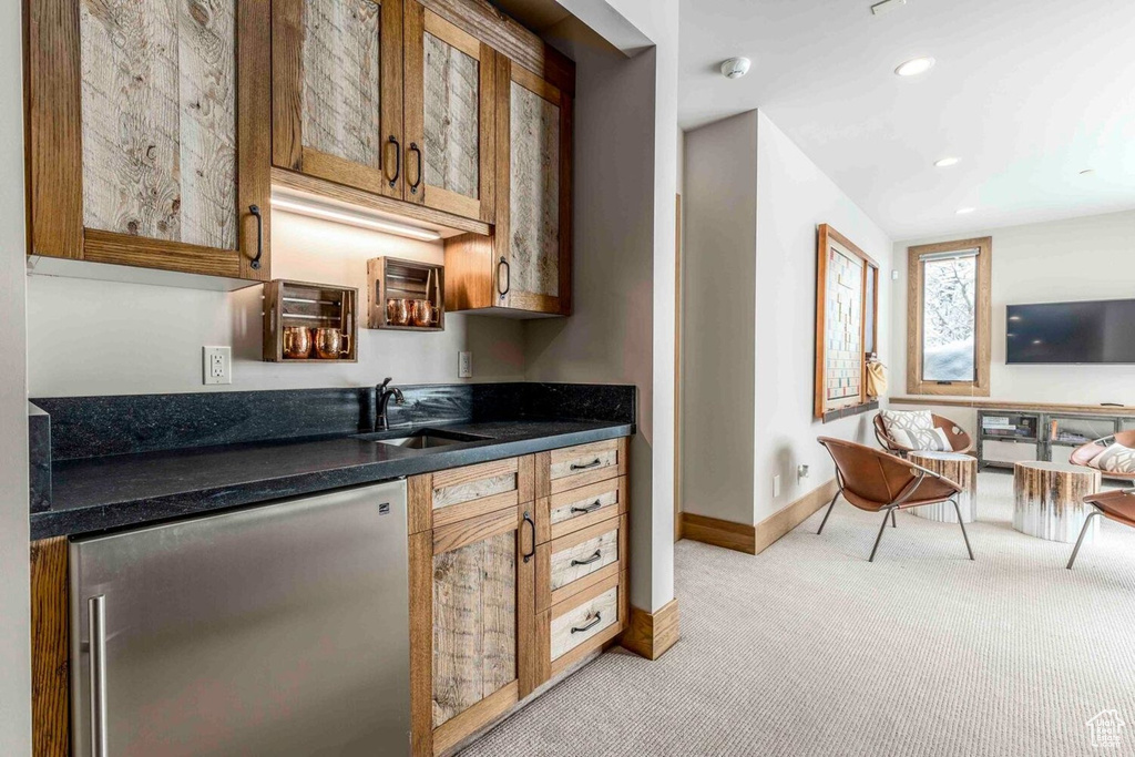 Bar area featuring light carpet, a sink, fridge, baseboards, and recessed lighting