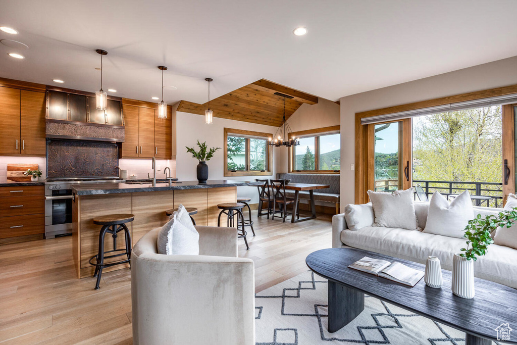 Living room with vaulted ceiling, light wood finished floors, recessed lighting, and a chandelier