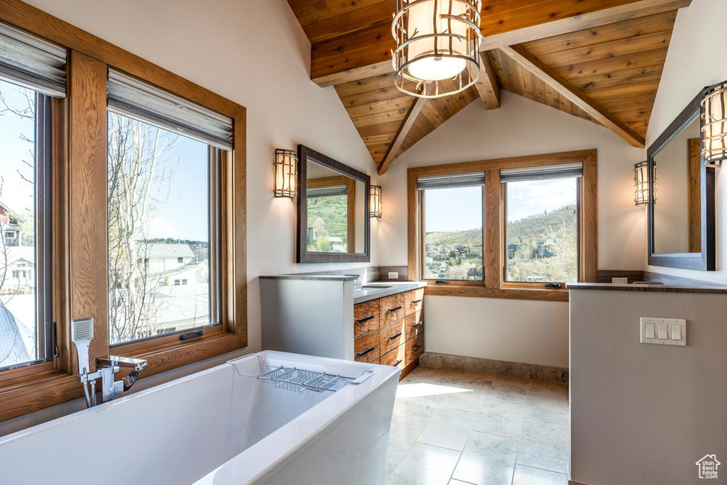 Bathroom featuring vanity, a bathtub, wooden ceiling, baseboards, and healthy amount of natural light