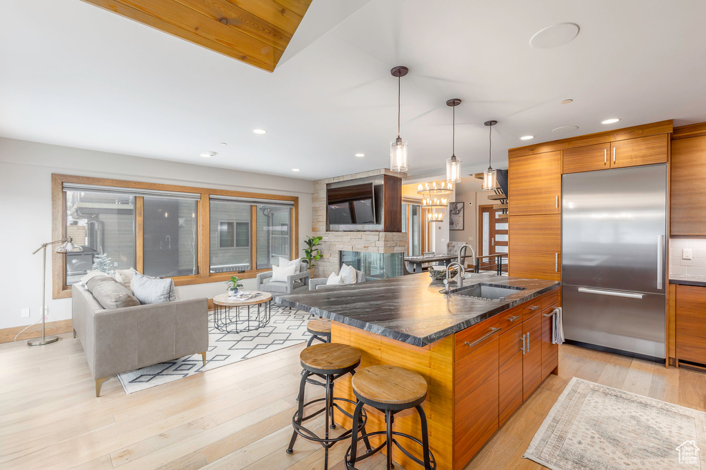 Kitchen with stainless steel built in fridge, brown cabinets, modern cabinets, a sink, and recessed lighting