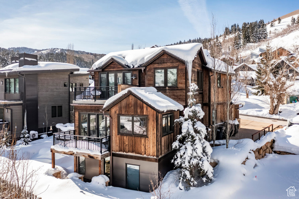 Snow covered rear of property with a balcony