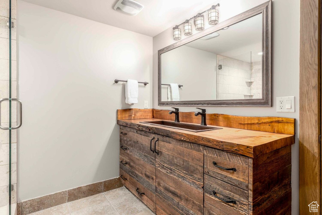 Full bath with a shower stall, baseboards, vanity, and tile patterned flooring