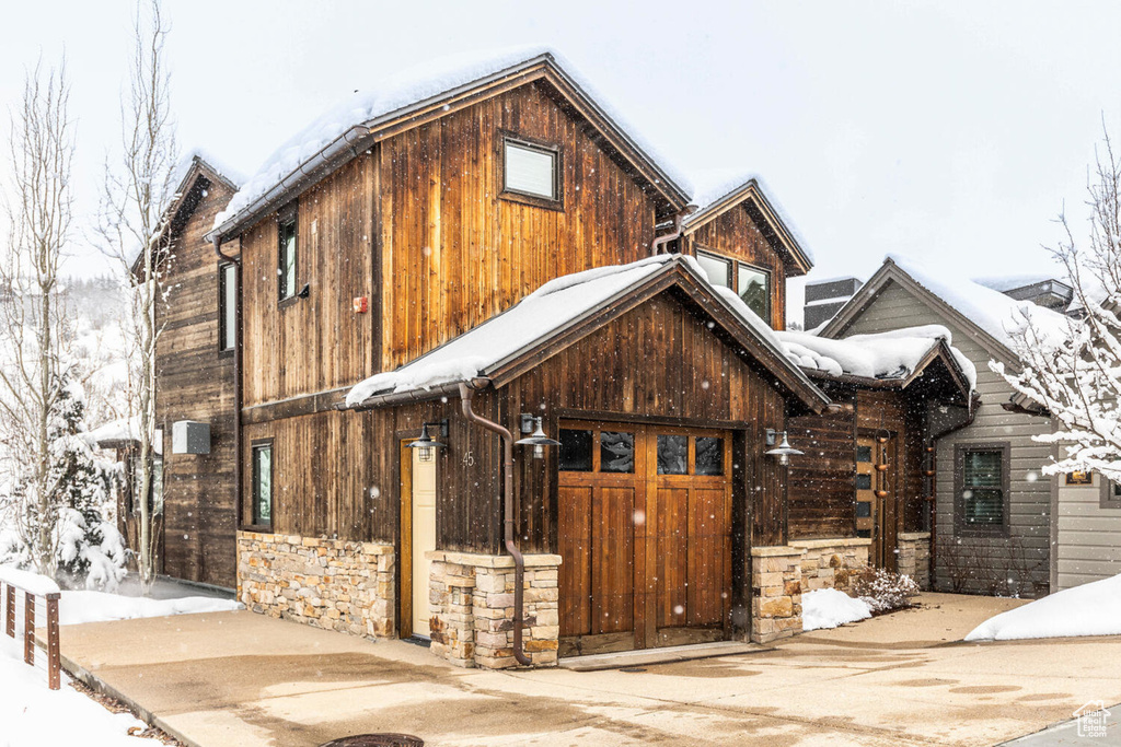 View of front facade with stone siding and a garage