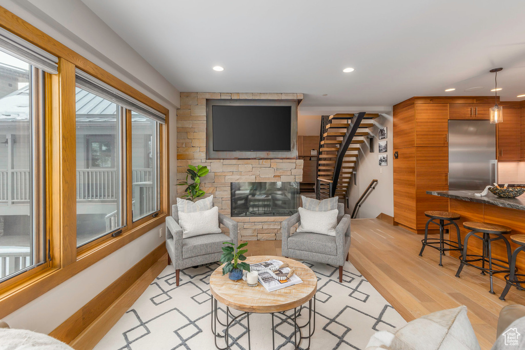 Living room with light wood-style flooring, stairs, recessed lighting, and a stone fireplace