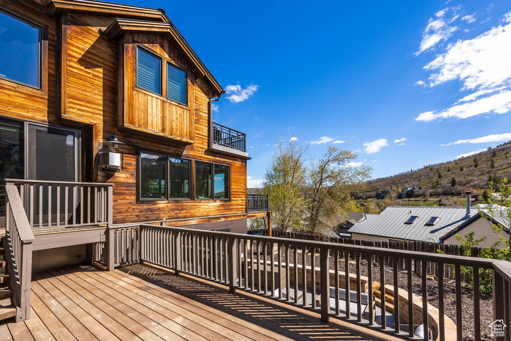 Wooden deck featuring a mountain view, a fenced backyard, and an AC wall unit