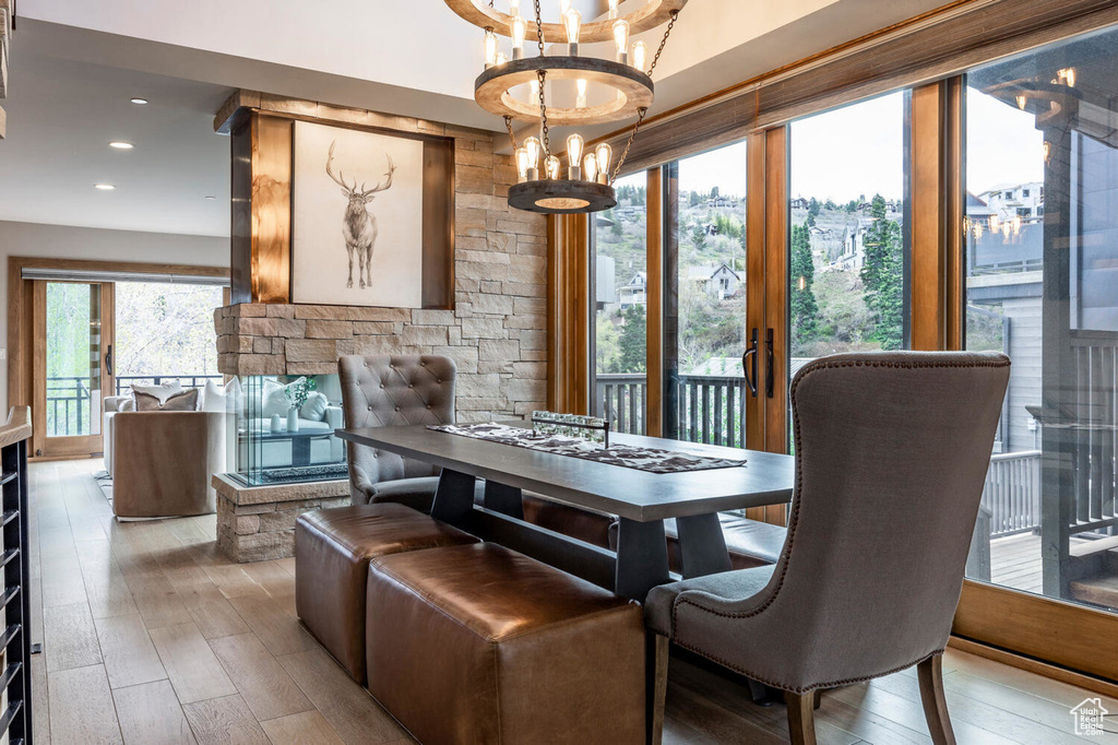 Dining room with a chandelier, wood-type flooring, a fireplace, and recessed lighting