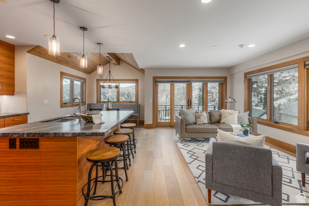 Kitchen featuring dark countertops, a kitchen bar, baseboards, and recessed lighting