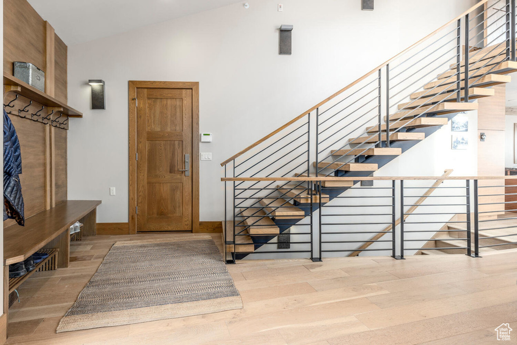 Entryway featuring wood finished floors, stairs, lofted ceiling, and baseboards