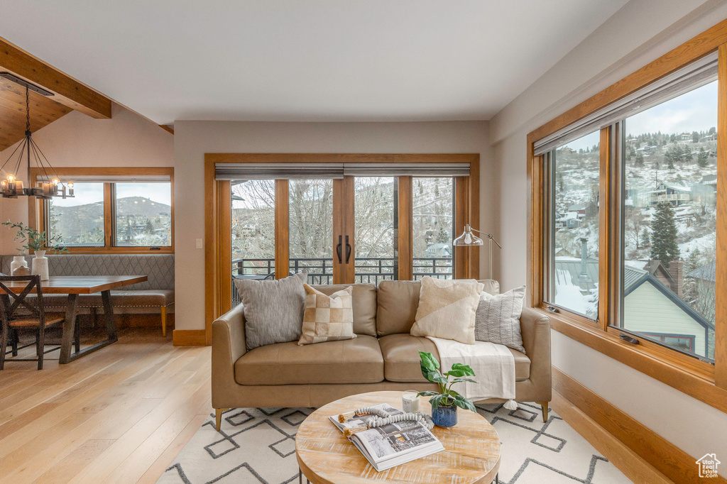 Living area featuring healthy amount of natural light, a chandelier, light wood-type flooring, and baseboards