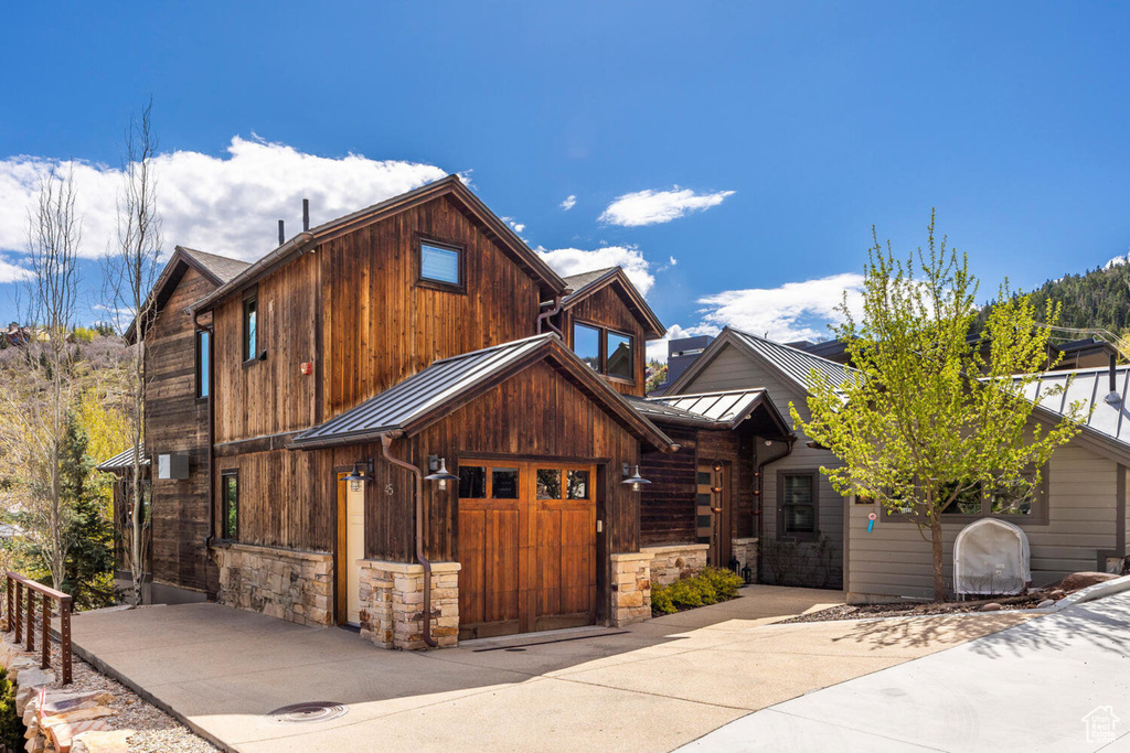 View of front of house with a standing seam roof, metal roof, and stone siding