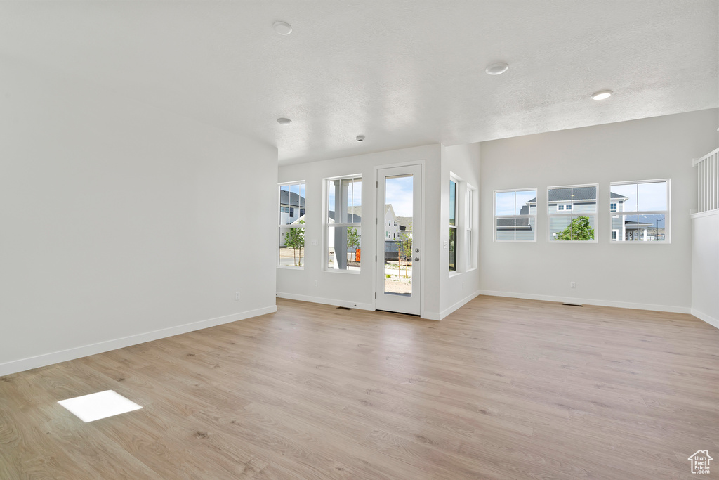 Unfurnished living room featuring light wood-type flooring and baseboards