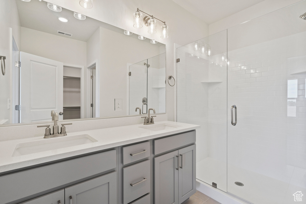 Full bath featuring a stall shower, double vanity, a spacious closet, and tile patterned floors