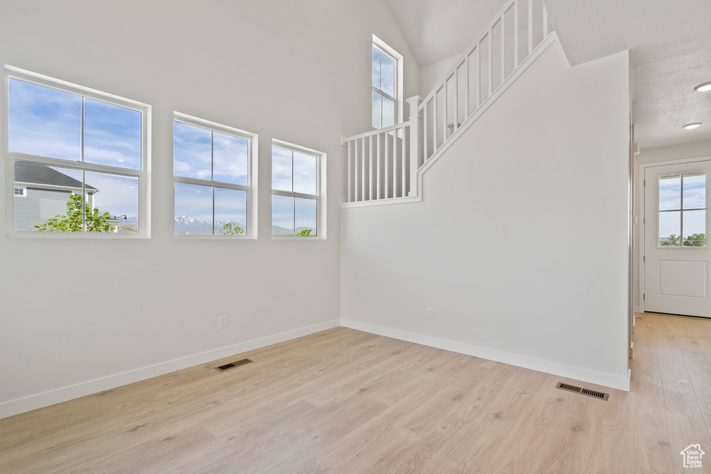 Spare room with light wood-style flooring, baseboards, and a high ceiling