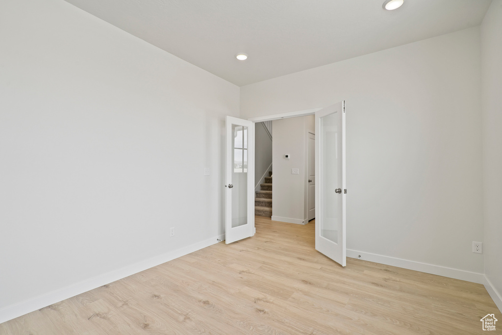 Unfurnished room with baseboards, light wood finished floors, recessed lighting, and stairs