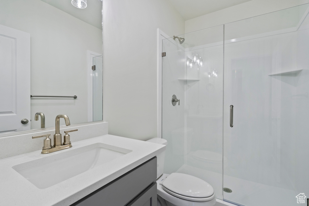 Full bath featuring a stall shower, toilet, and vanity