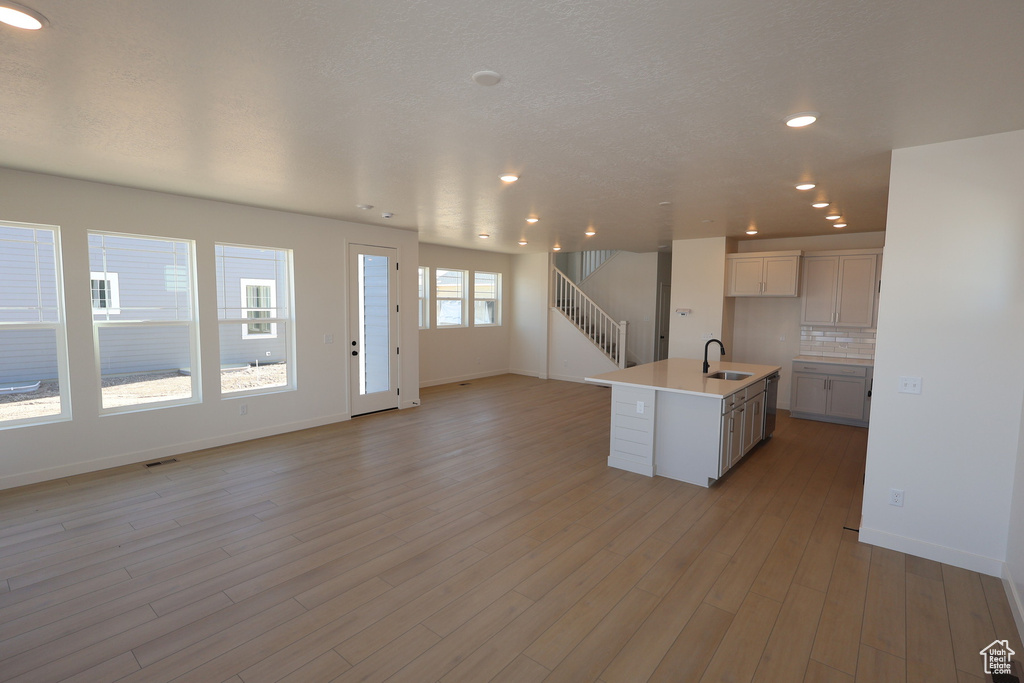 Kitchen with backsplash, baseboards, open floor plan, light wood-style floors, and a sink