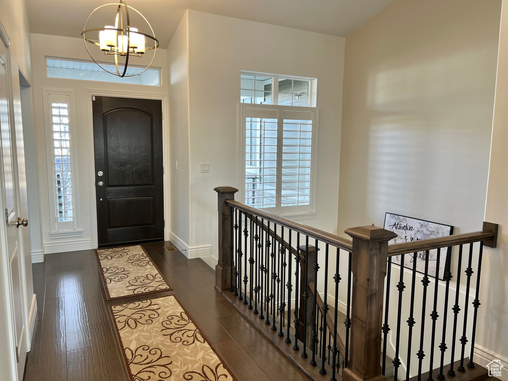 Entryway with dark wood-type flooring and an inviting chandelier